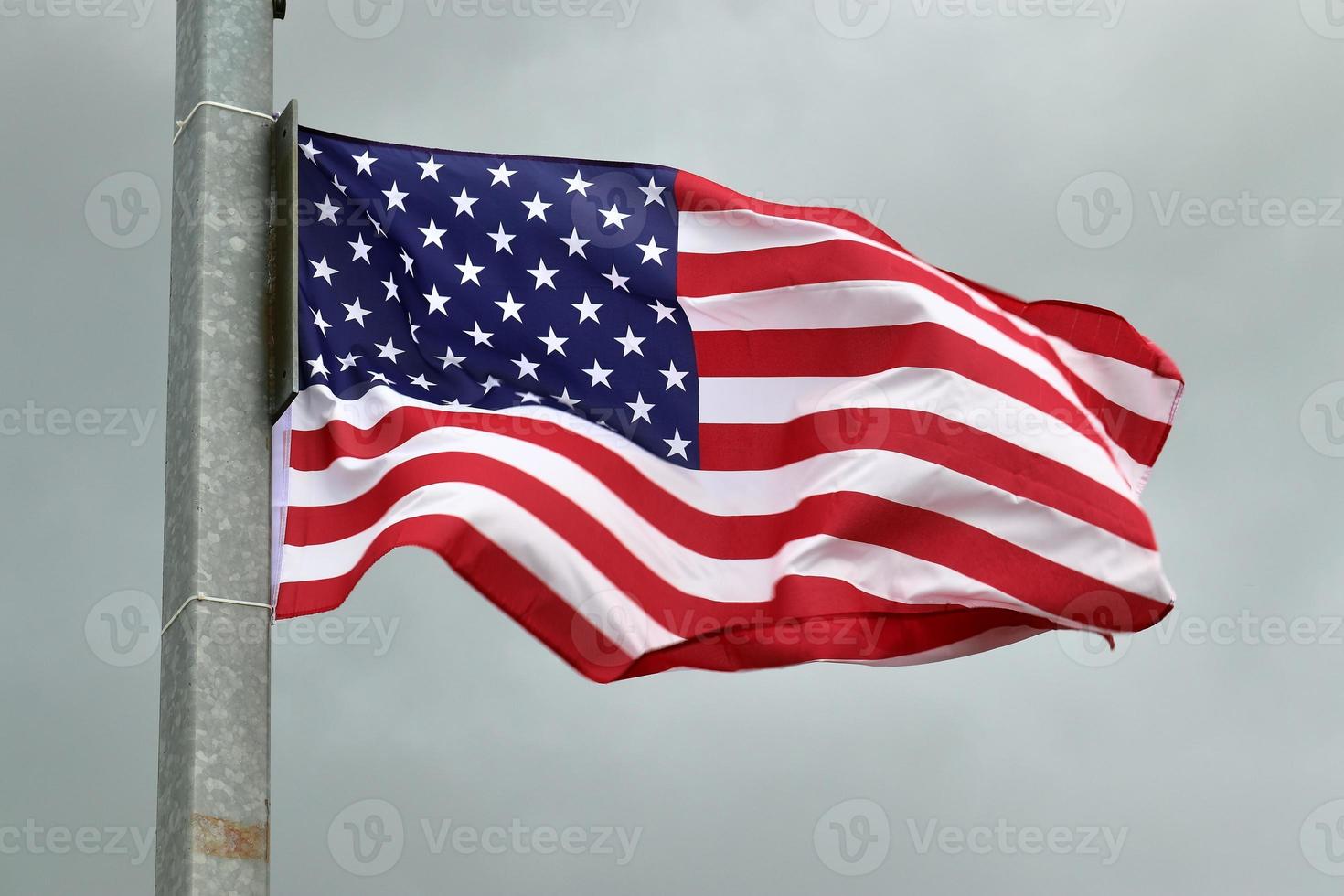 USA-Flagge an einem Fahnenmast, der sich langsam im Wind gegen den Himmel bewegt foto