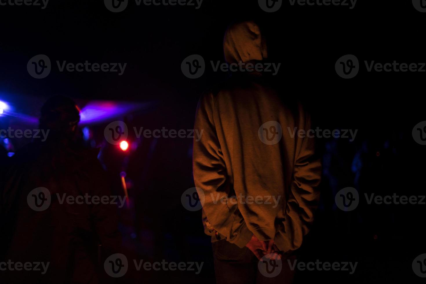 Typ nachts in der Disco. kerl steht mit dem rücken beim konzert. Mann im Licht der Unterhaltungsmusik. foto