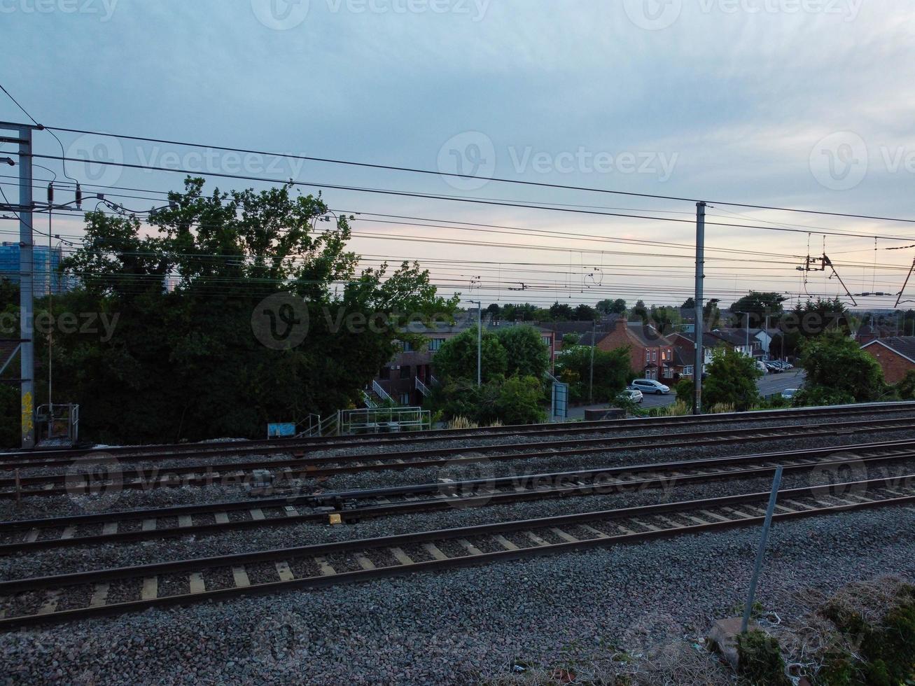 Luftaufnahmen Hochwinkelansicht der Stadt Luton in England und des Bahnhofs und des Zuges auf Gleisen bei Sonnenuntergang foto