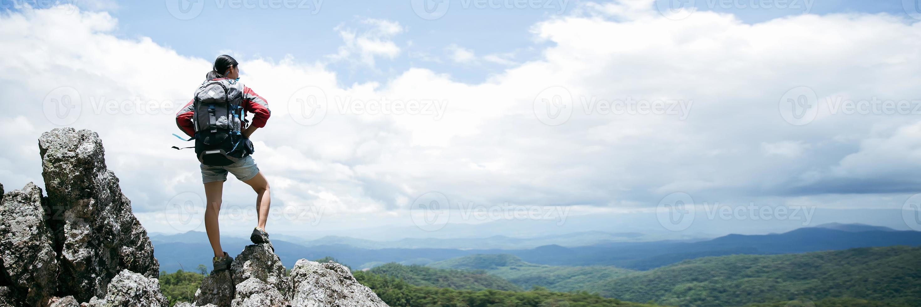 junge frau, die auf einem felsen steht, rucksackfrau, die im sommer einen schönen berg betrachtet, landschaft mit sportmädchen, panoramahügel, wald. Reisen und Tourismus. Banner mit Kopierbereich foto