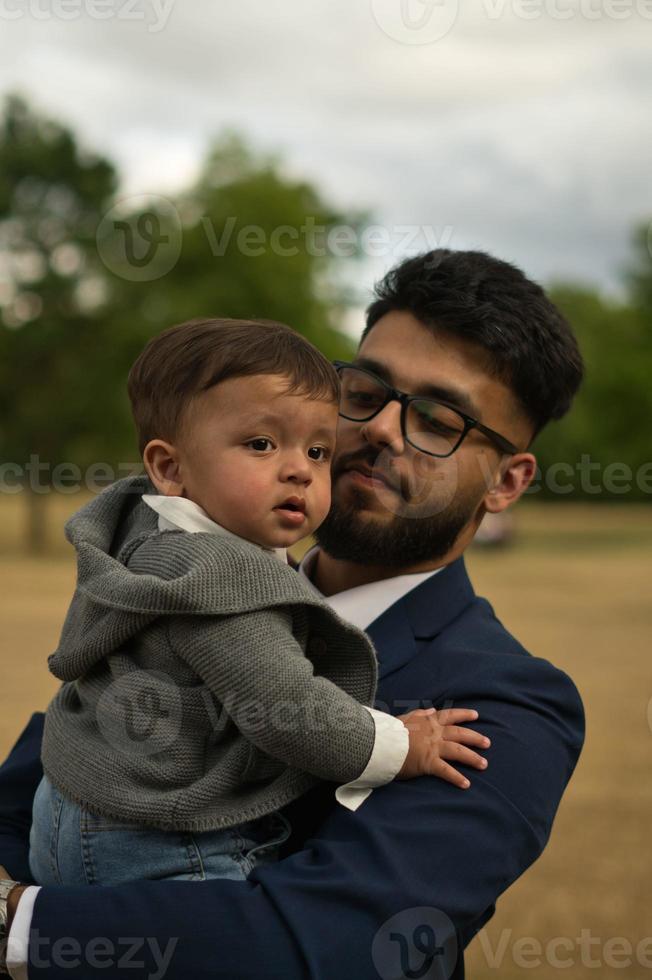 Der asiatische pakistanische Vater hält sein 11 Monate altes Kind im örtlichen Park foto