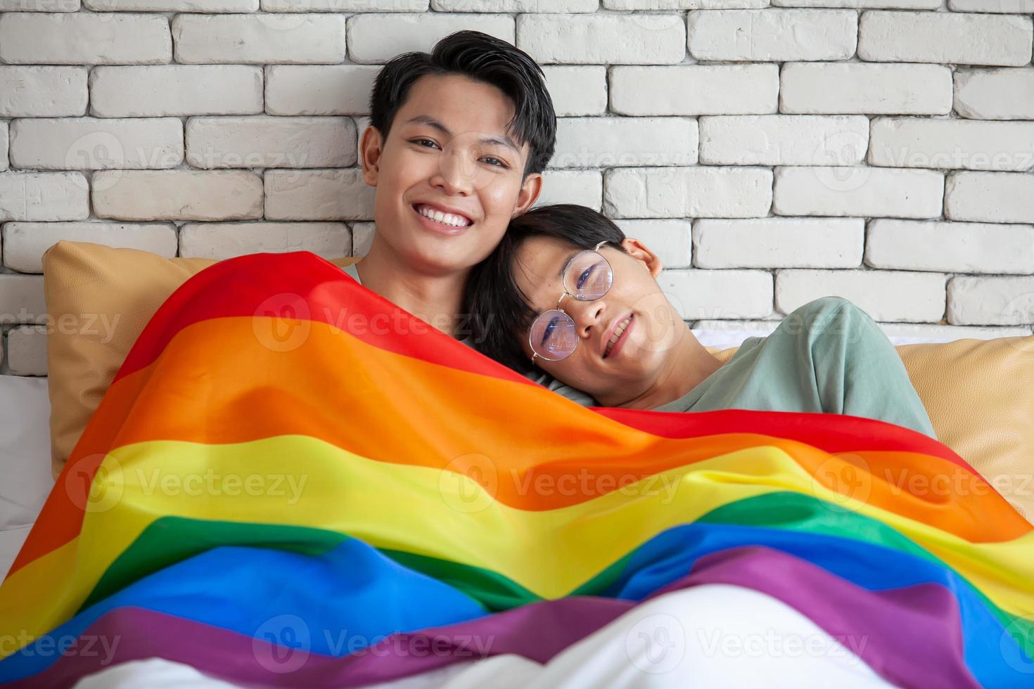 glückliches asiatisches homosexuelles paar, das zusammen spricht und sich zu hause auf dem bett entspannt, lgbtq-konzept. foto