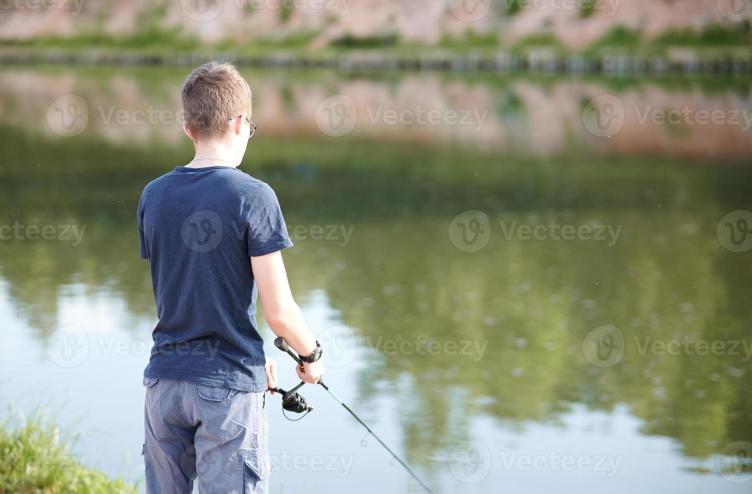 junger mann, der auf see mit rute fischt. reise-lifestyle-konzept sommerferien. foto