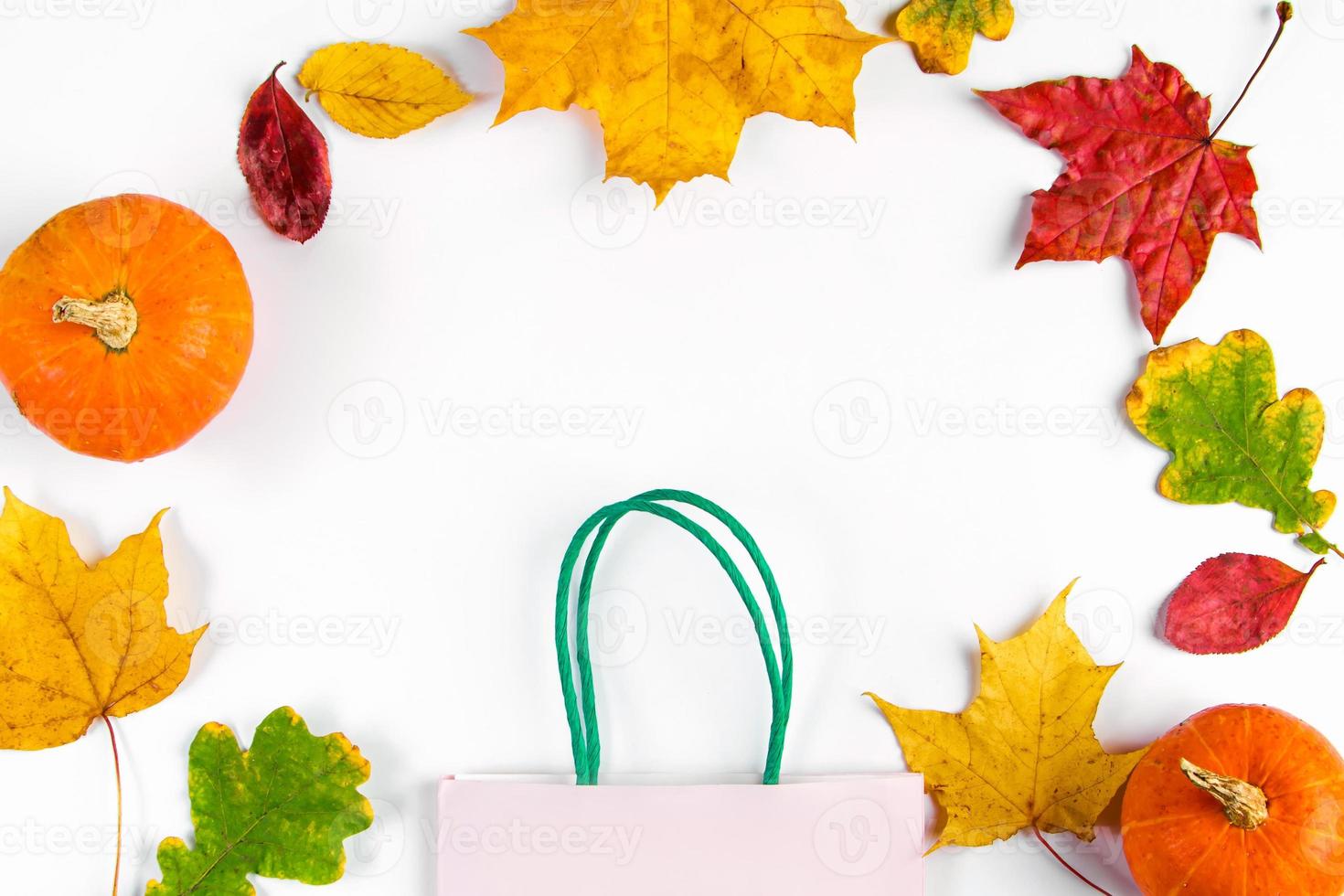 Papiereinkaufstasche und bunte Laub auf weißem Hintergrund. Herbstverkaufskonzept. Rabatt-Banner. foto