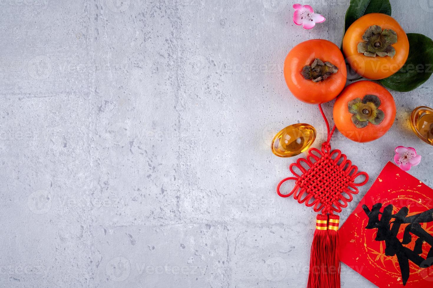 Draufsicht auf frische süße Persimonen mit Blättern auf grauem Tischhintergrund für das chinesische Neujahrsfest foto