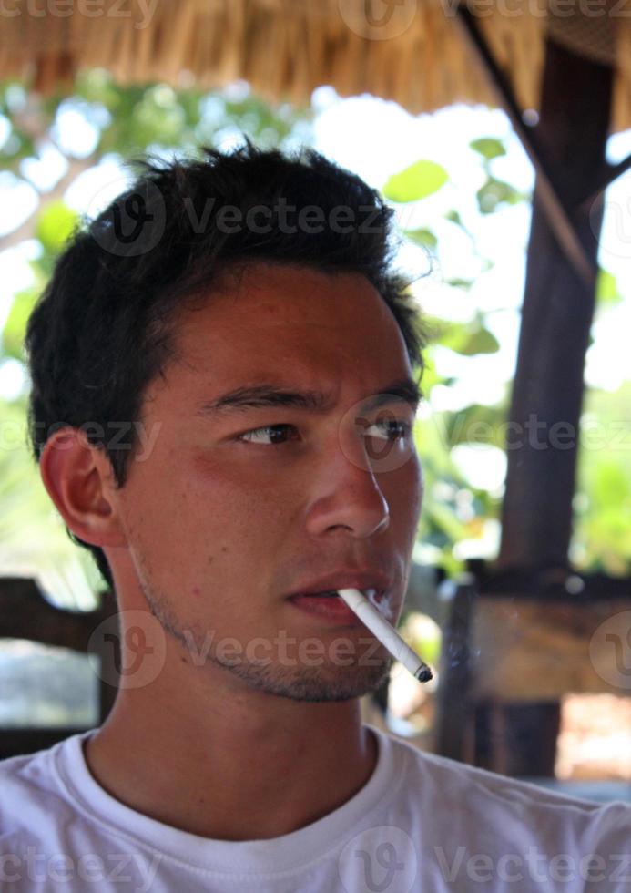 hübscher junger Mann mit einer Bräune und einer Zigarette in einer Bar foto