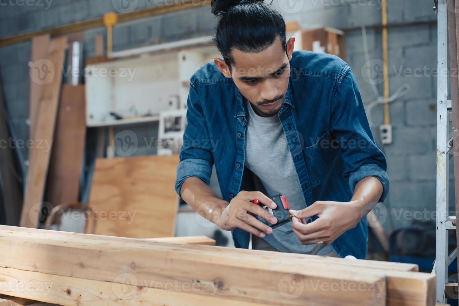 junger asiatischer tischler, der in der holzhandwerkstischlerei arbeitet. foto