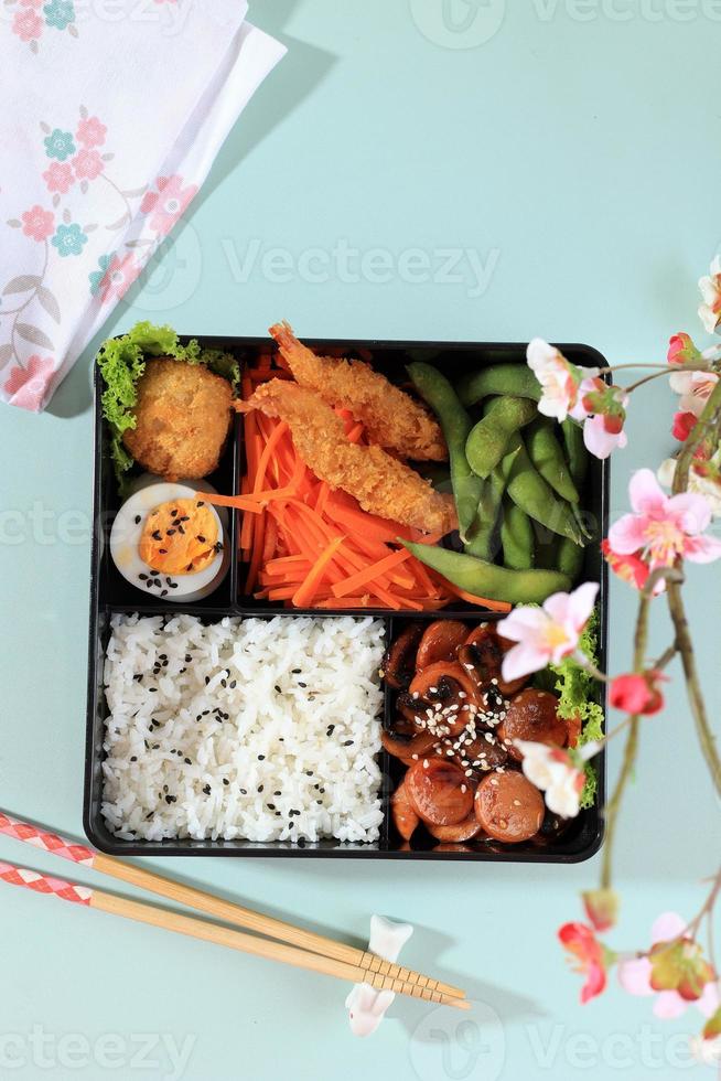 draufsicht japanische bento-brotdose mit gedämpftem gemüse, gekochtem ei, nugget, wurst, edamame und tempura. foto