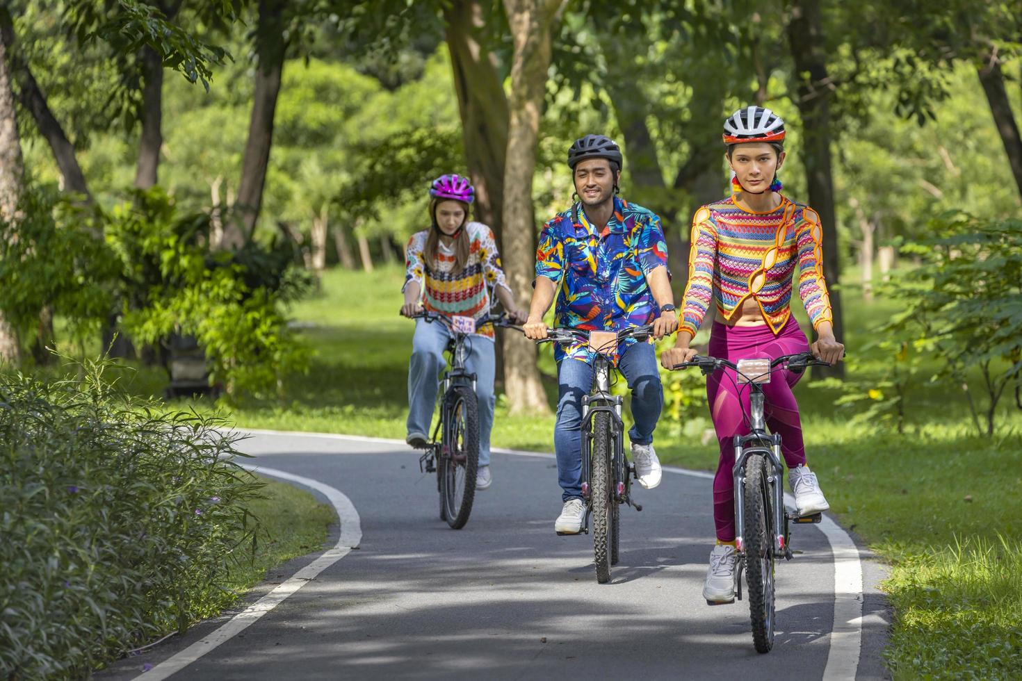Team asiatischer Radsportfreunde, die im öffentlichen Park im Radweg mit Fahrrad auf der Brücke mit grünem Waldhintergrund fahren foto