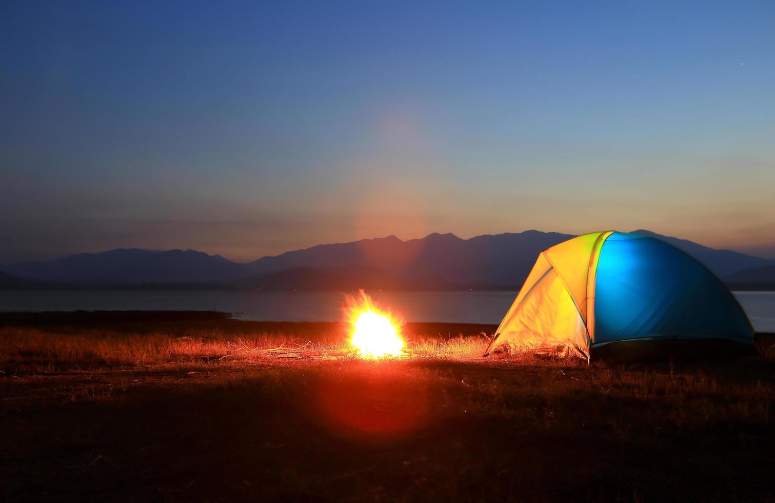 Zelt und Lagerfeuer bei Sonnenuntergang am See foto