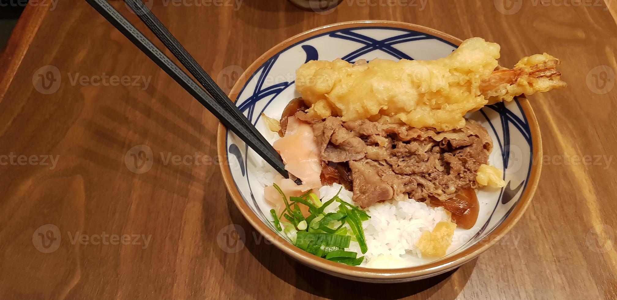 japanisches traditionelles essen rindfleisch teriyaki mit stickt-reis und tempura-garnelen geschnittenen frühlingszwiebeln in einer schüssel foto
