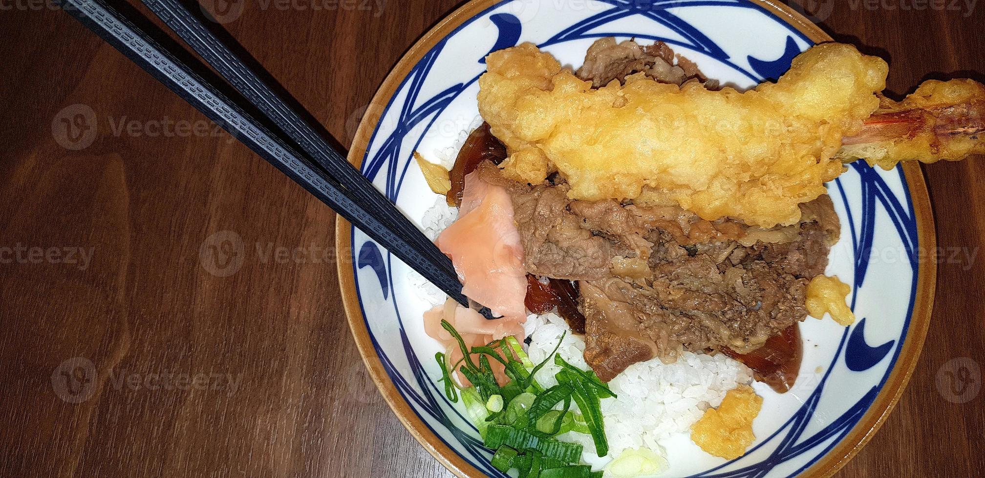 japanisches traditionelles essen rindfleisch teriyaki mit stickt-reis und tempura-garnelen geschnittenen frühlingszwiebeln in einer schüssel foto