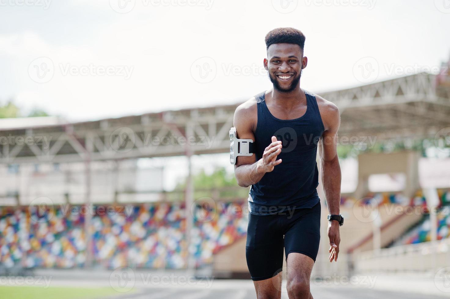 afroamerikanischer männlicher athlet in sportbekleidung, der allein auf einer laufbahn im stadion rennt. foto