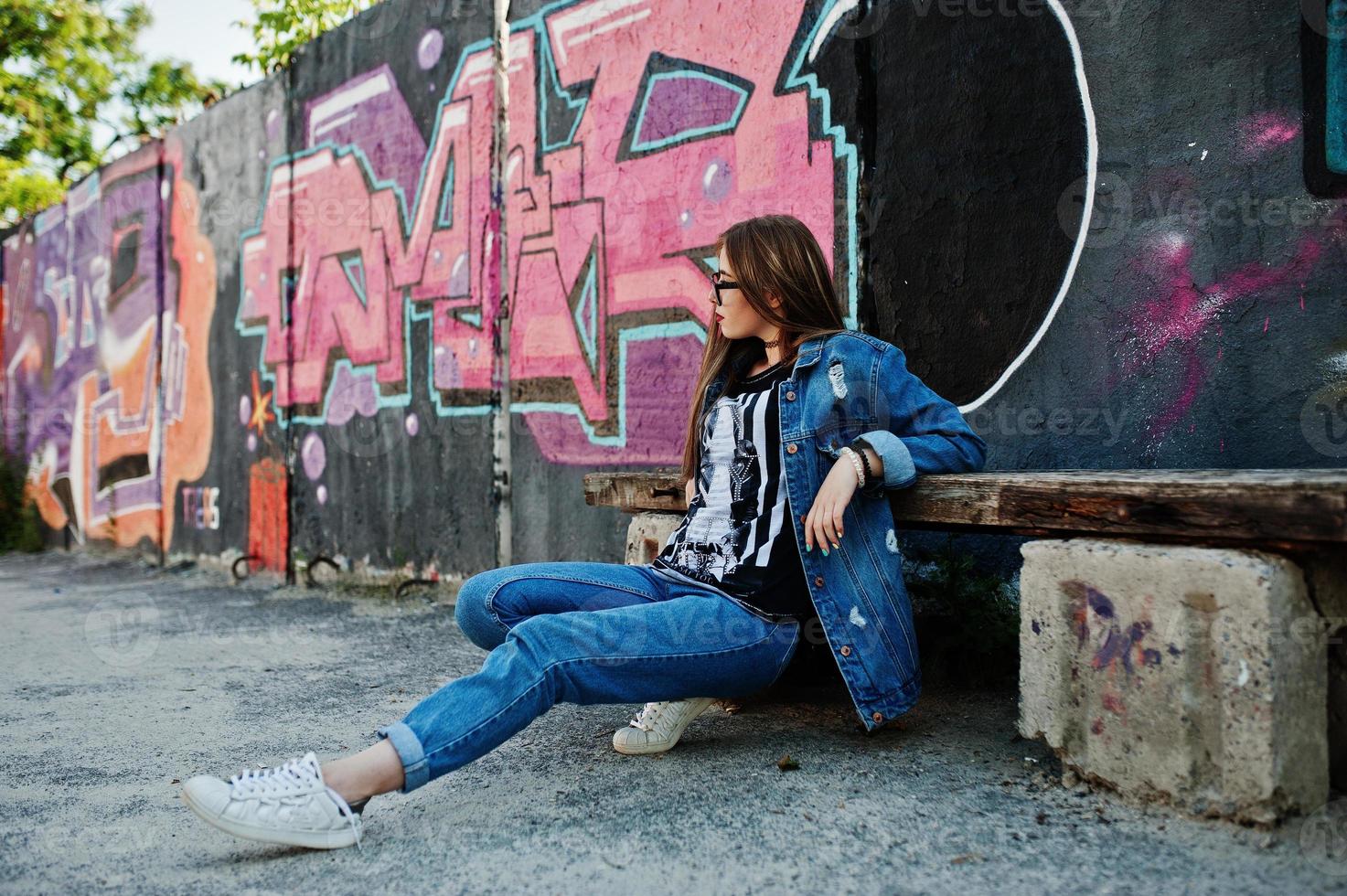 stylisches, lässiges Hipster-Mädchen in Jeans und Brille gegen große Graffiti-Wand. foto