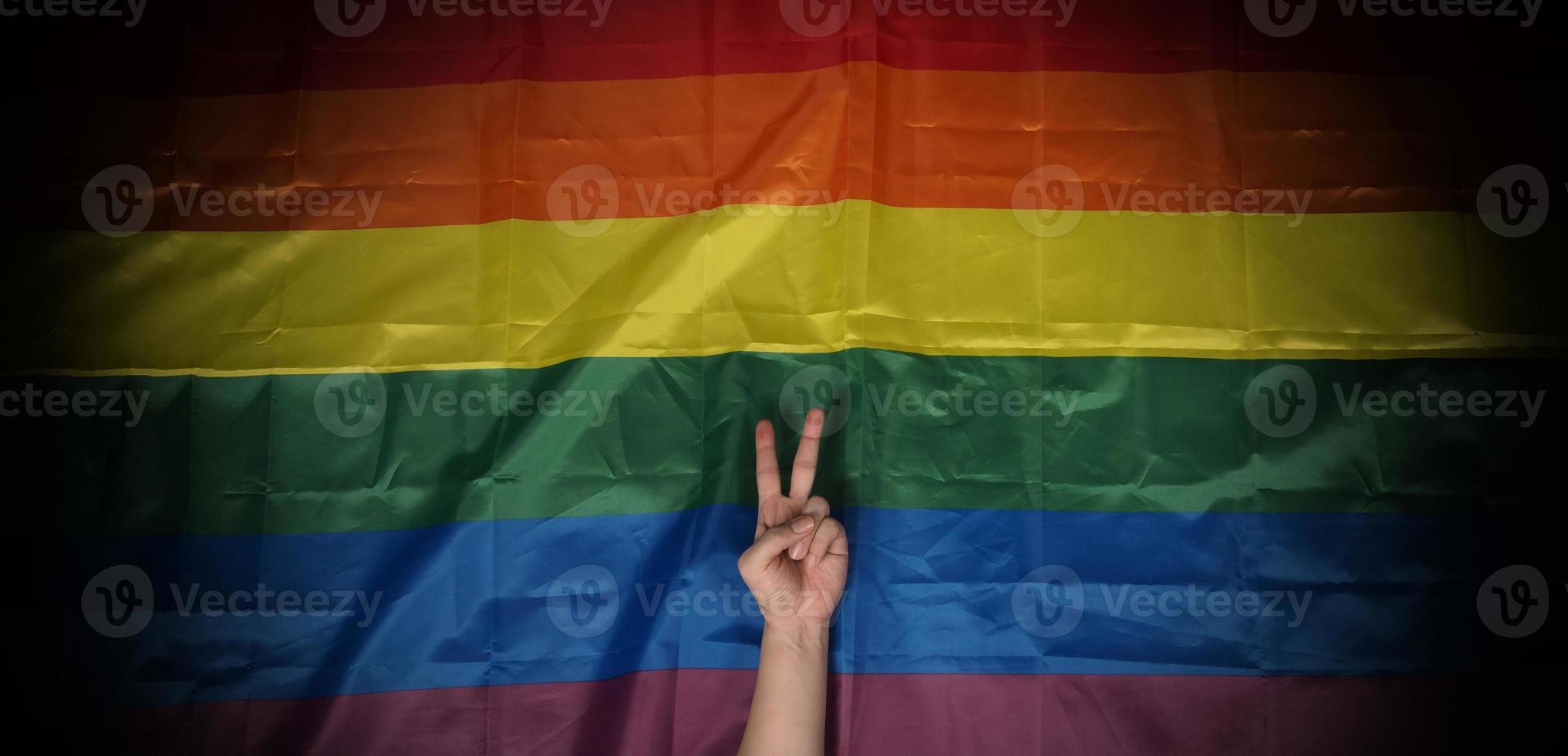 lgbtq-stolzflagge auf schwarzem hintergrund. lgbt-regenbogenfahne in schwuler hand. foto