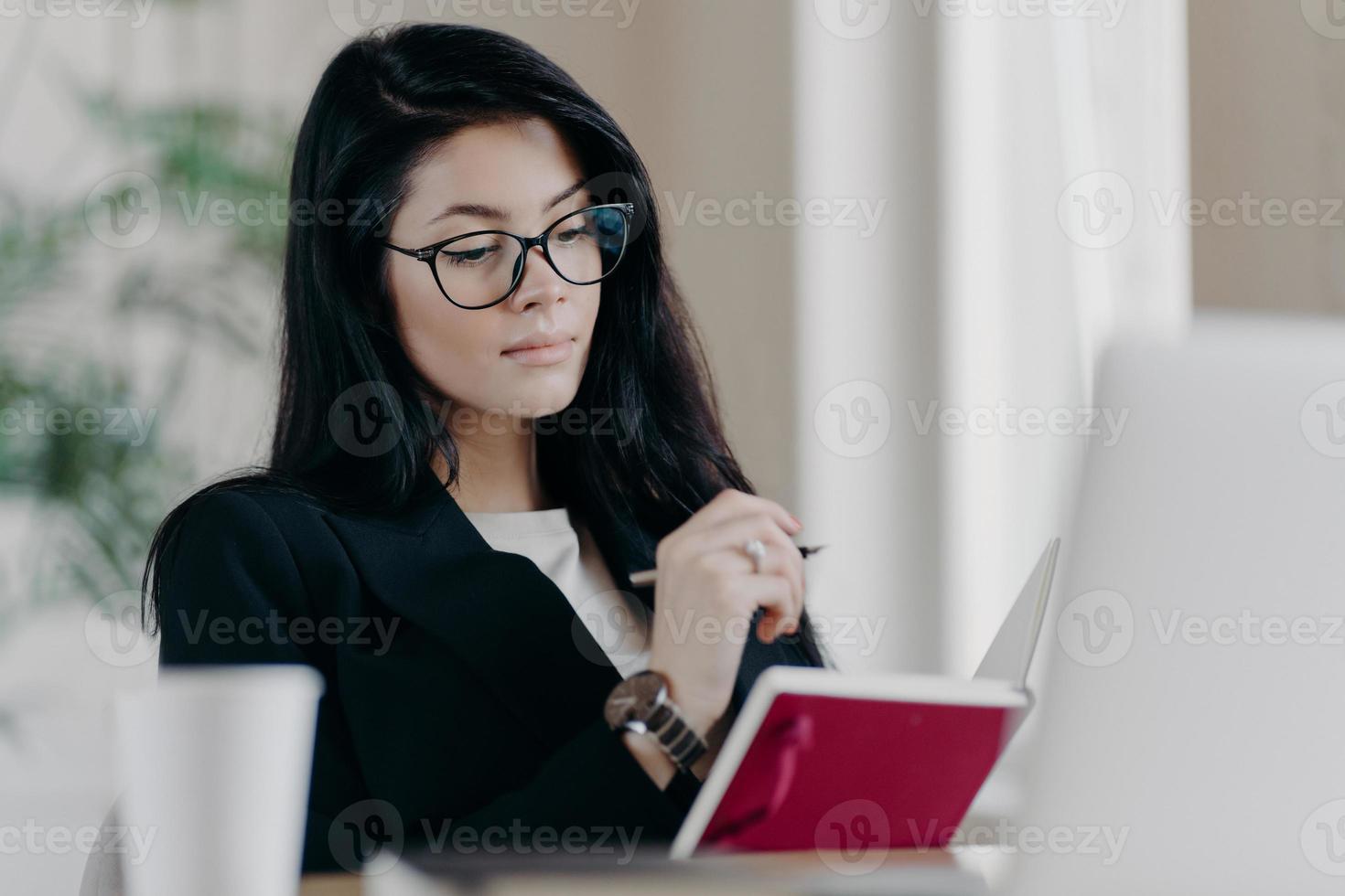 intelligente intelligente lehrerin mit brille zur sehkorrektur lernt online-kurse, macht sich notizen im notizblock, während sie webinar ansieht, arbeitet aus der ferne, plant projektaufgaben. menschen, berufskonzept foto