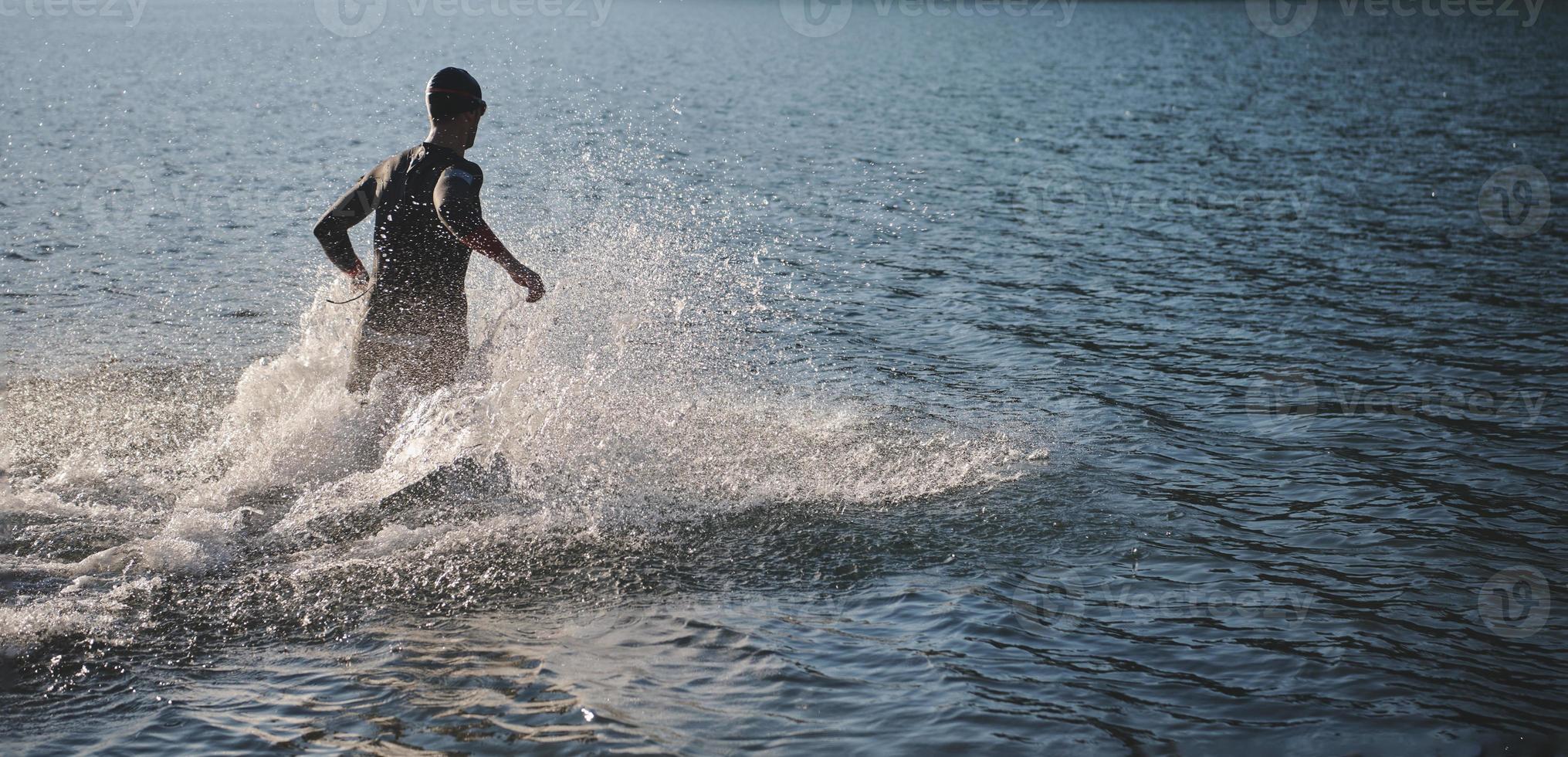 Triathlonsportler beginnt mit dem Schwimmtraining auf dem See foto