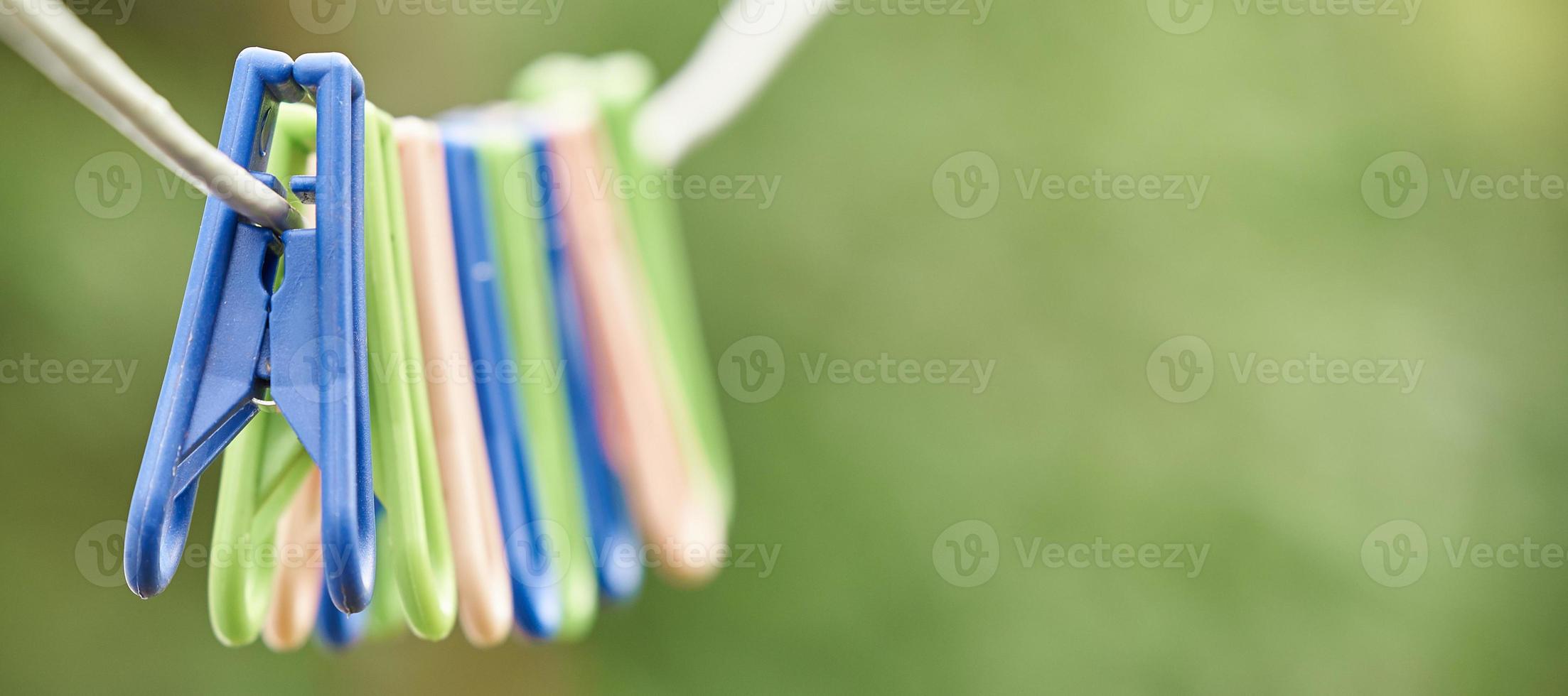 Wäscheklammern aus Kunststoff Bunte Wäscheklammern aus Kunststoff hängen in einer Reihe an einem Seil. Foto mit Kopierbereich.