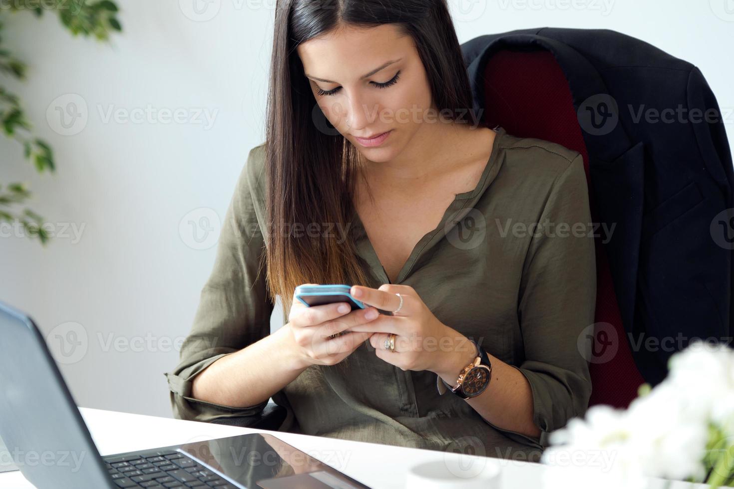 Geschäftsfrau, die mit Handy in ihrem Büro arbeitet. foto