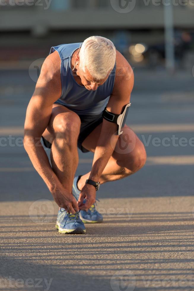 Mann bindet Laufschuhe Schnürsenkel foto