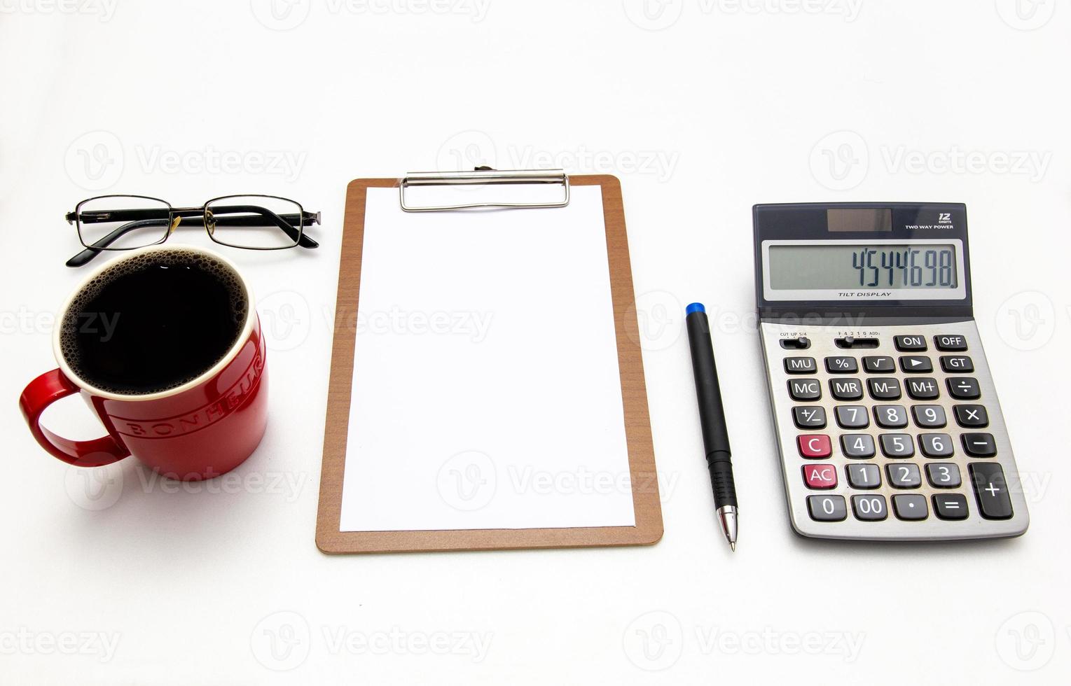 die Draufsicht des Schreibtisches auf weißem Hintergrund leeres Papier, Stift, Taschenrechner, Gläser, Kaffee. finanzplanung und arbeitskonzept. foto