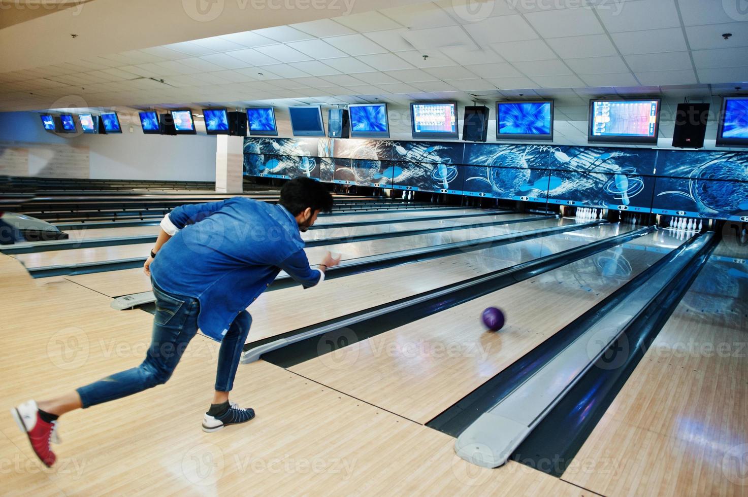 unscharfes Foto eines asiatischen Mannes aus dem hinteren Süden wirft eine Bowlingkugel auf die Gasse.