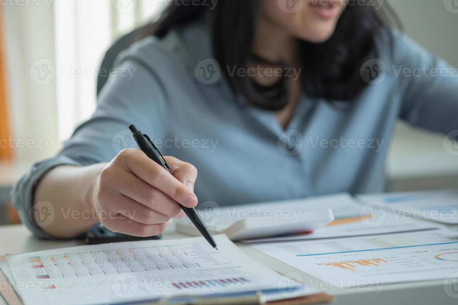 Geschäftsfrau, die einen Stift hält, um dem Vorgesetzten über einen Laptop-Computer Gewinndaten in Diagrammen zu präsentieren. foto