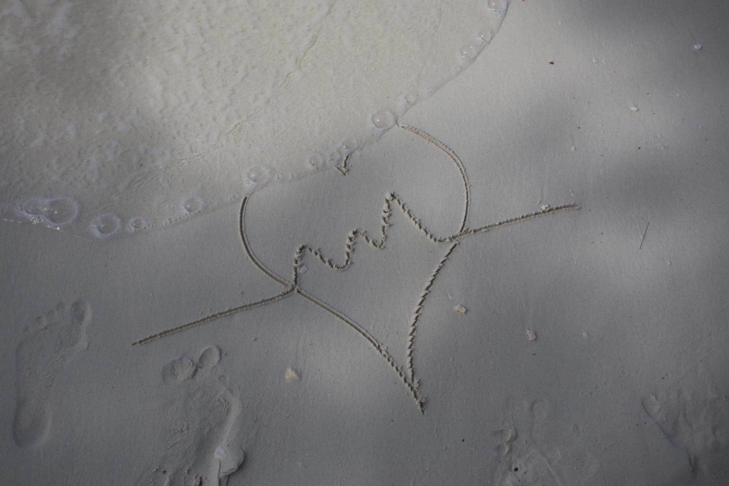 Herzen auf den Sand eines Strandes gezeichnet foto