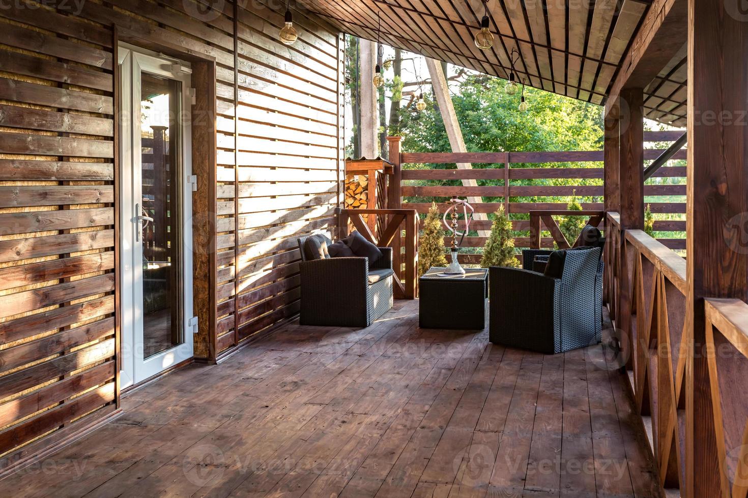 Innenraum der leeren Hallenveranda im Holzdorf-Ferienhaus mit Vintage-Lampen und Stühlen foto