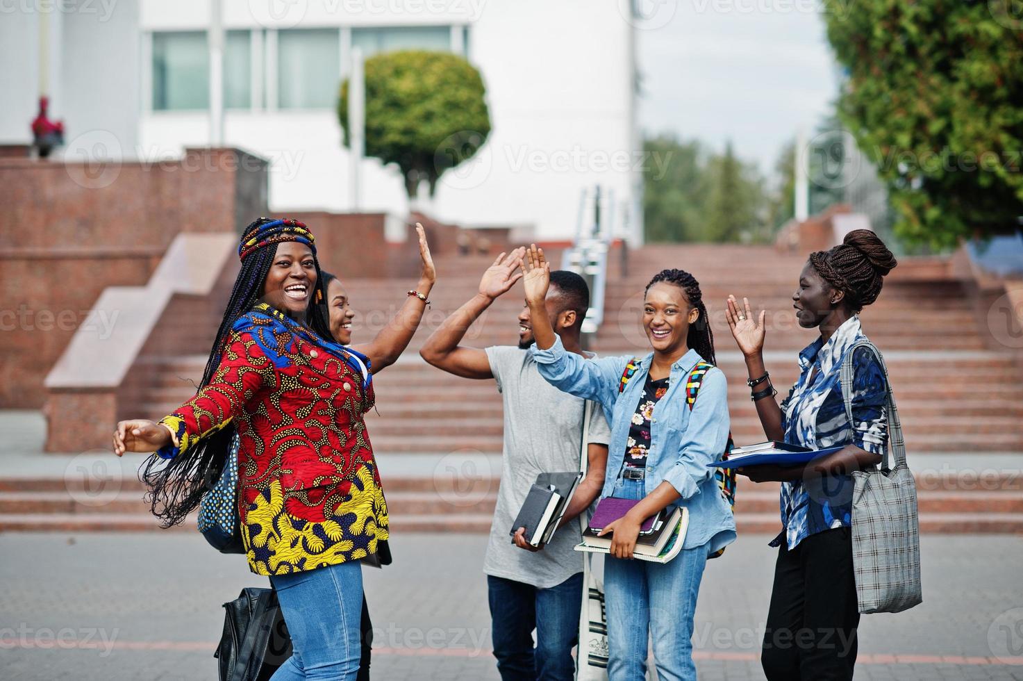 Gruppe von fünf afrikanischen College-Studenten, die gemeinsam Zeit auf dem Campus des Universitätshofs verbringen. Schwarze Afro-Freunde studieren und geben sich High Five. foto