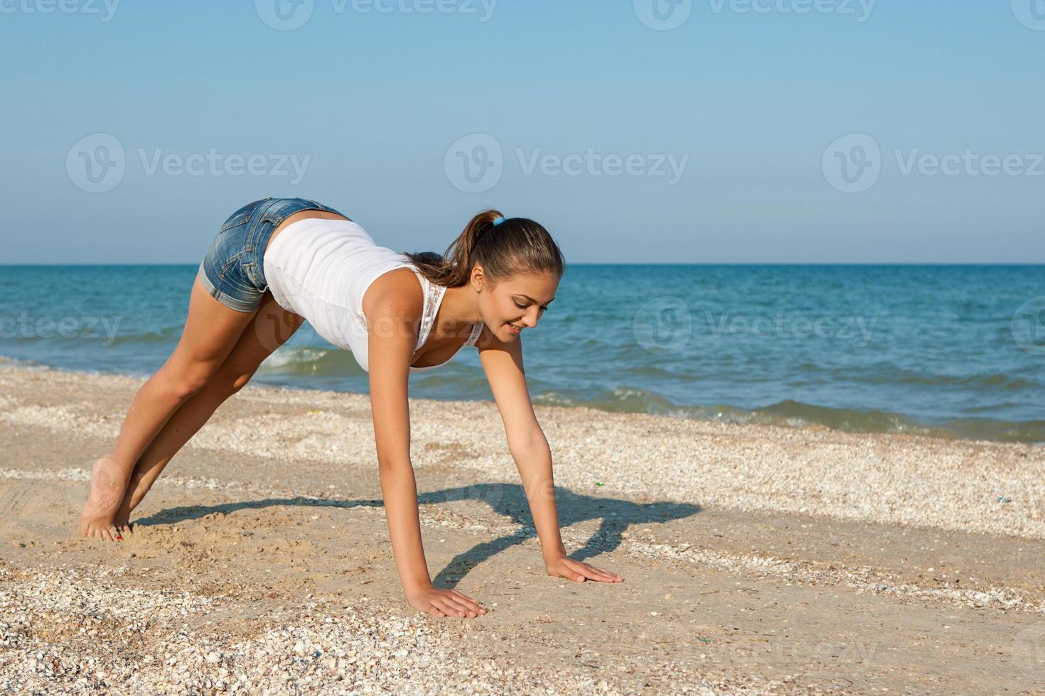 junge Frau, die Yoga oder Fitness am Meer praktiziert foto