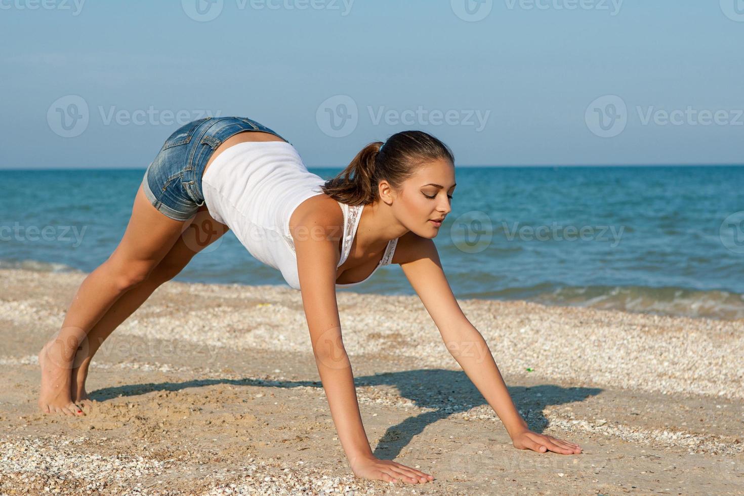 junge Frau, die Yoga oder Fitness am Meer praktiziert foto
