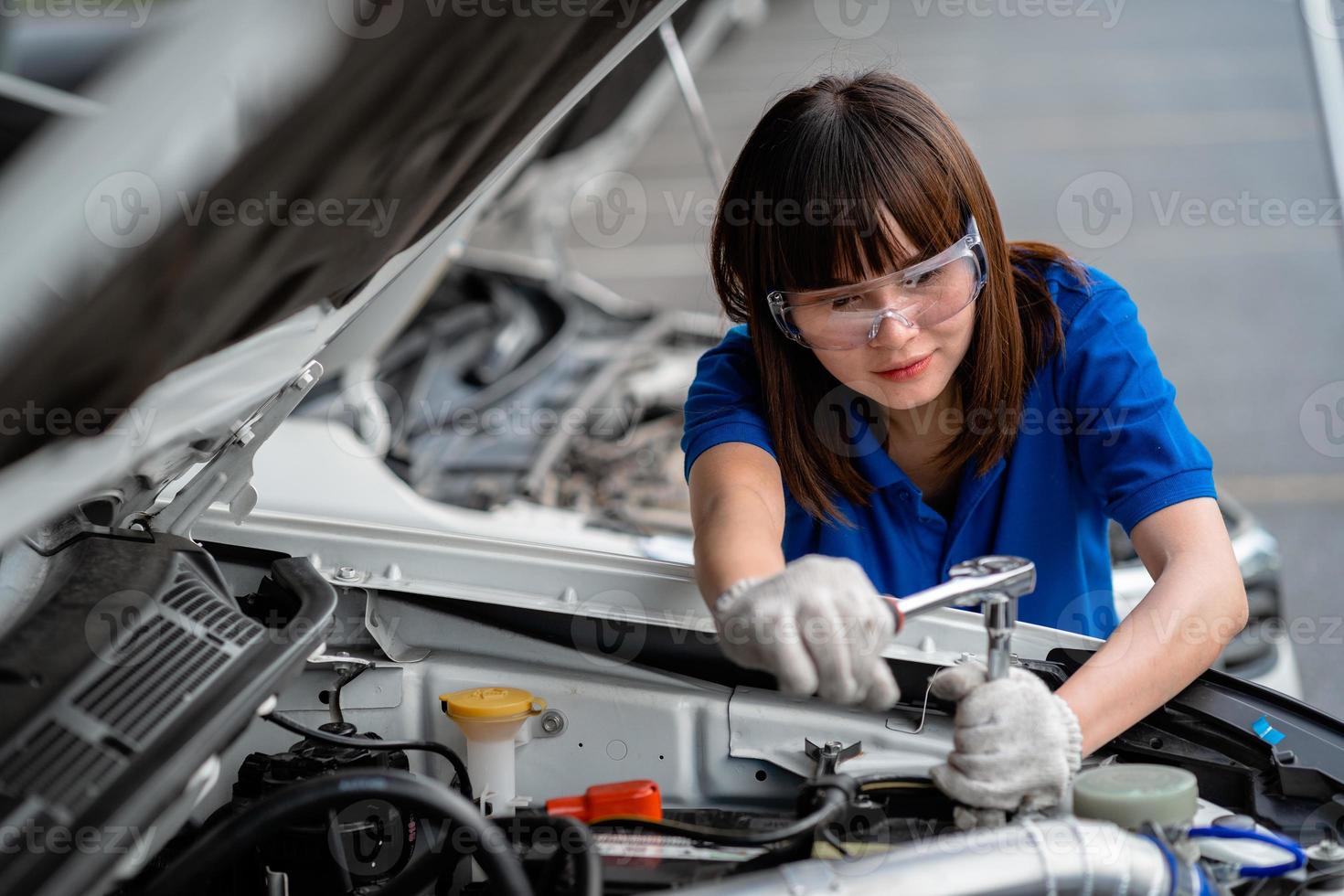 eine Kfz-Mechanikerin, die den Motor eines Autos überprüft. Ein Mechaniker inspiziert und wartet den Motor eines Autos oder Fahrzeugs. eine Kfz-Mechanikerin, die den Motor eines Autos überprüft. Automechaniker-Konzept foto