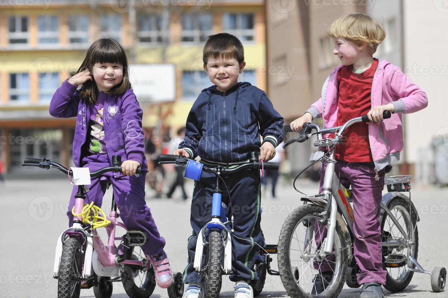 glückliche kindergruppe, die lernt, fahrrad zu fahren foto