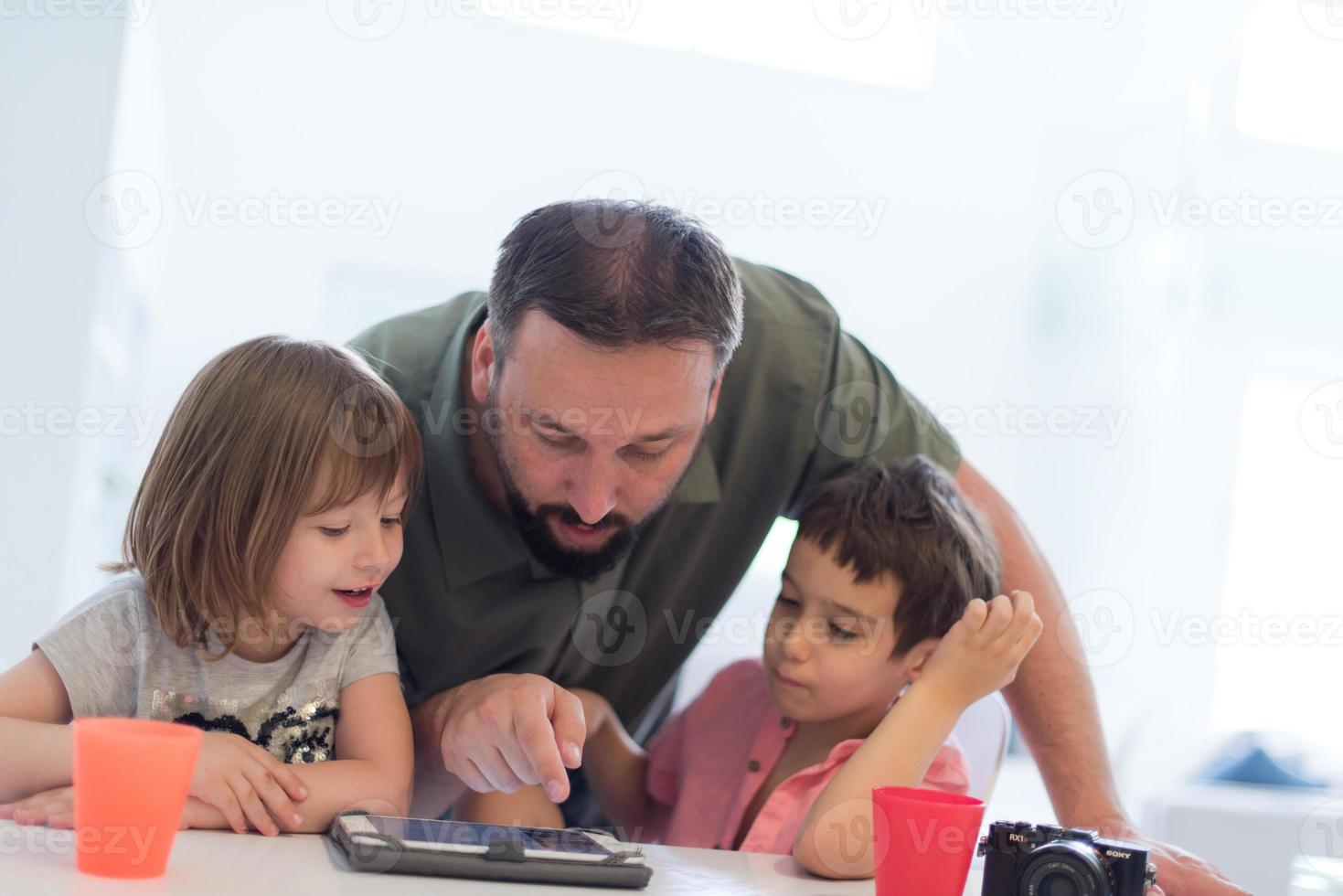 alleinerziehender vater zu hause mit zwei kindern, die spiele auf dem tablet spielen foto