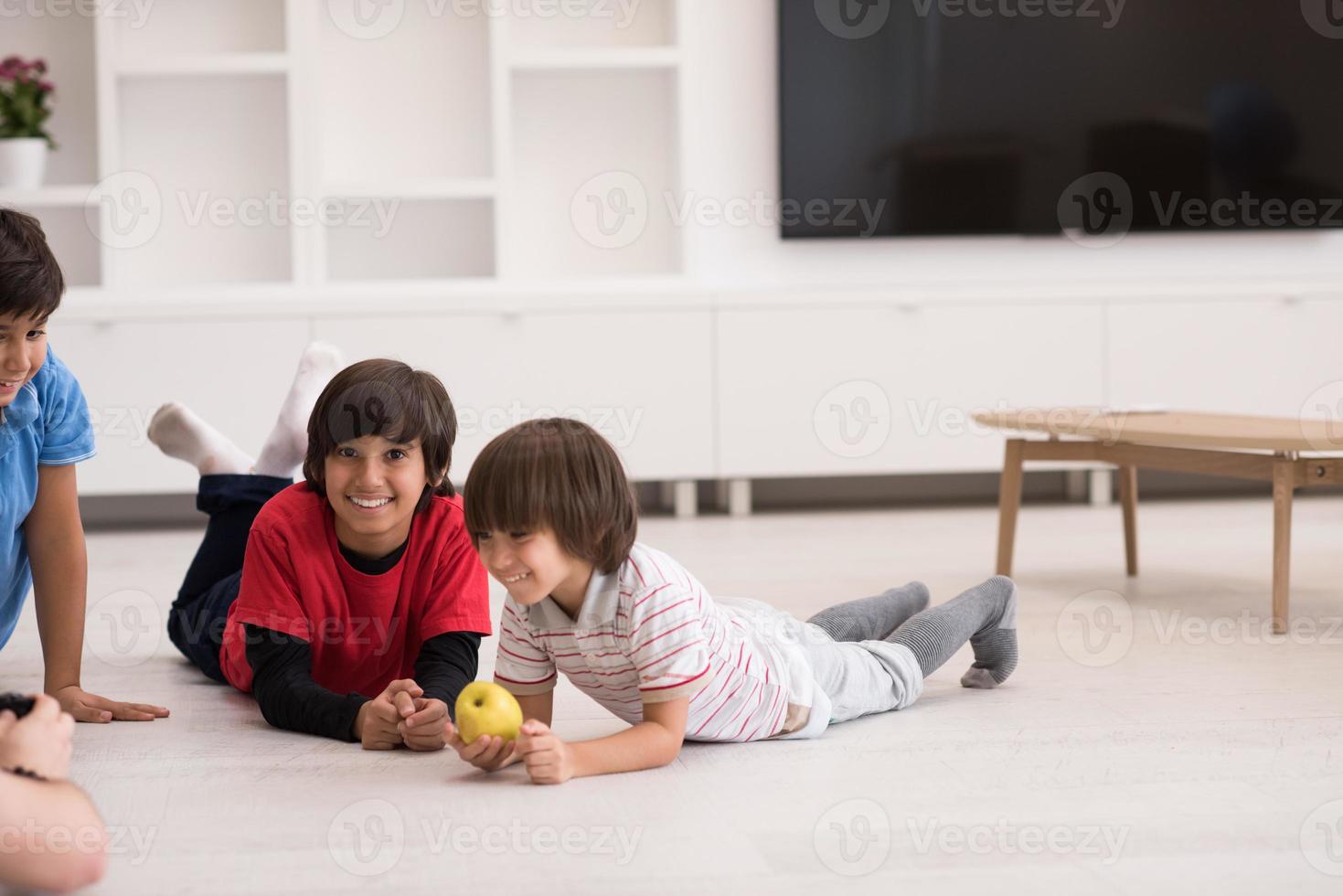 jungen, die spaß mit einem apfel auf dem boden haben foto