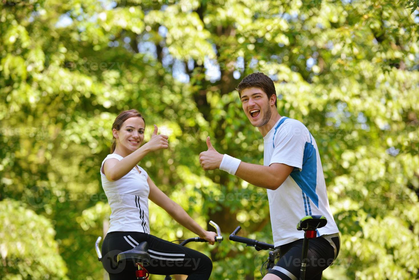 Glückliches Paar, das im Freien Fahrrad fährt foto