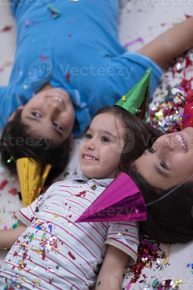 Kinder blasen Konfetti, während sie auf dem Boden liegen foto