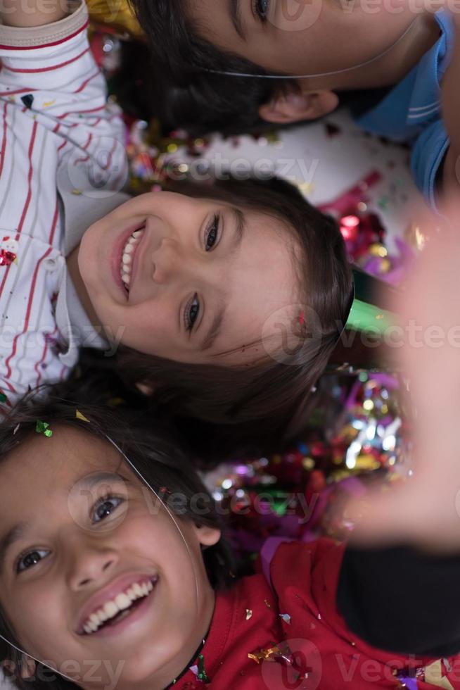 Kinder blasen Konfetti, während sie auf dem Boden liegen foto