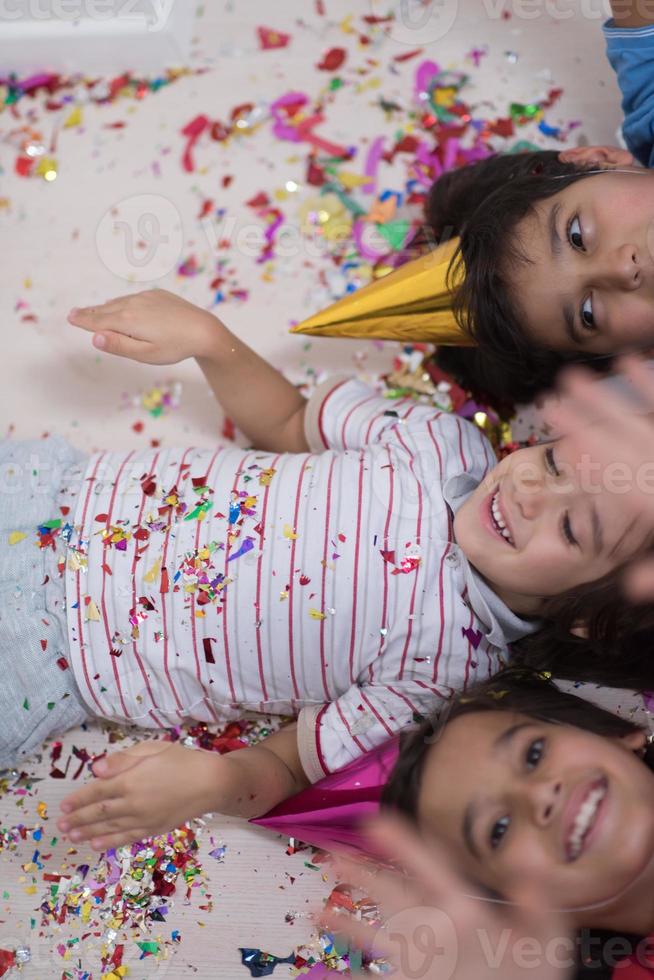 Kinder blasen Konfetti, während sie auf dem Boden liegen foto