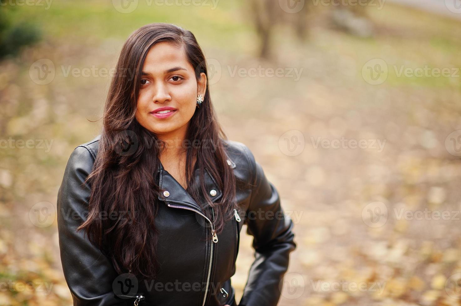 Nahaufnahme Porträt eines hübschen indischen Mädchens in schwarzem Saree-Kleid und Lederjacke, das im Freien auf der Herbststraße posiert. foto