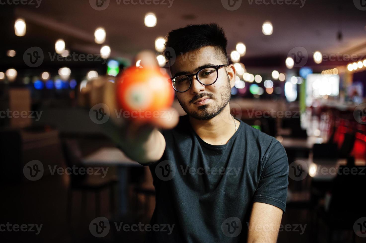 stilvoller asiatischer mann hält poolbillardkugel. foto