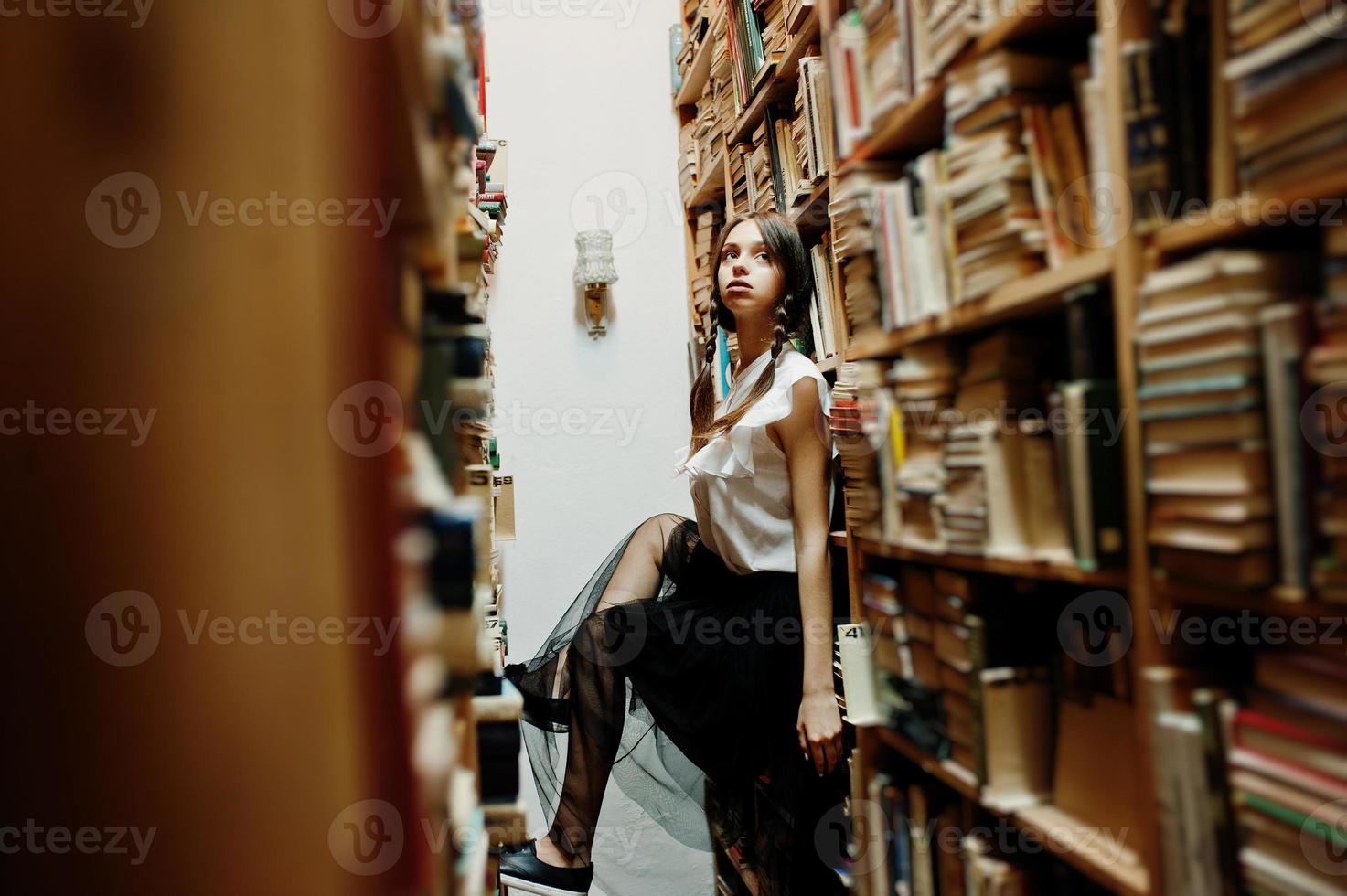 Mädchen mit Zöpfen in weißer Bluse in der alten Bibliothek. foto