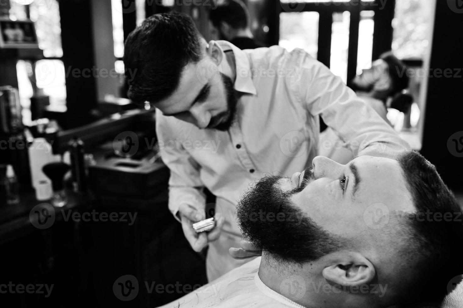 hübscher bärtiger mann im friseursalon, friseur bei der arbeit. foto