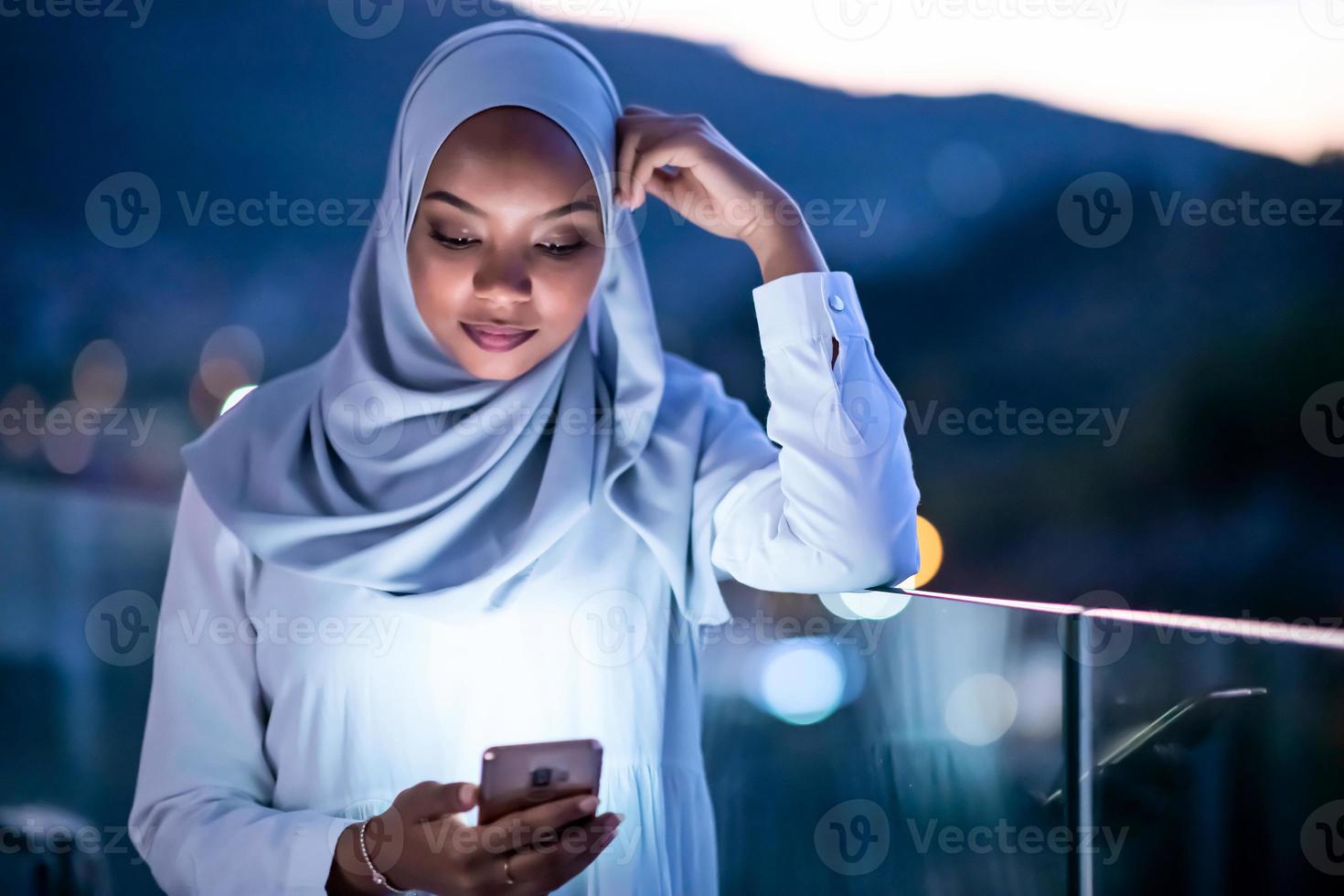 junge muslimische frau auf der straße nachts mit telefon foto