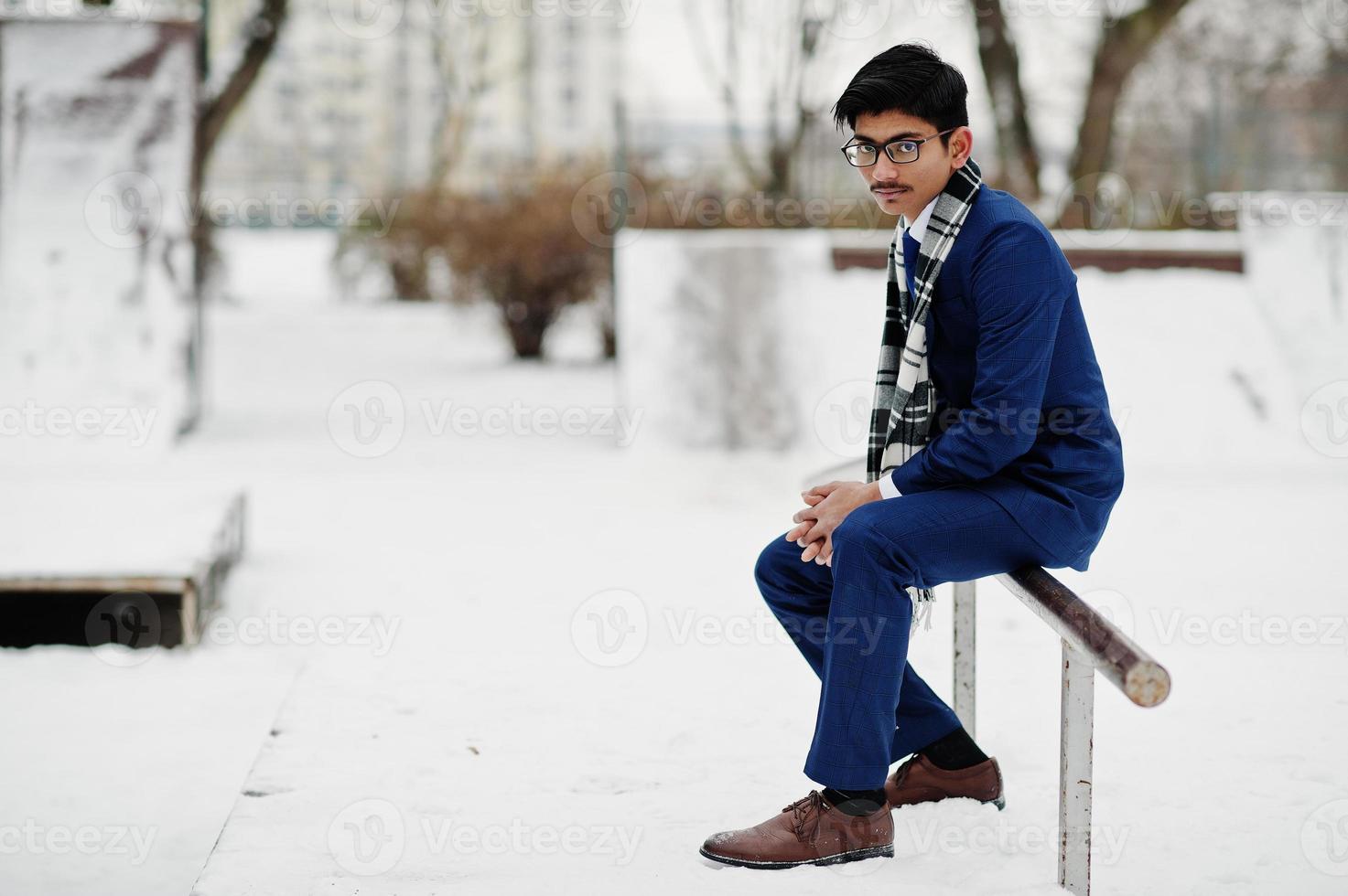 stilvoller indischer studentenmann in anzug, brille und schal posierte am wintertag im freien. foto