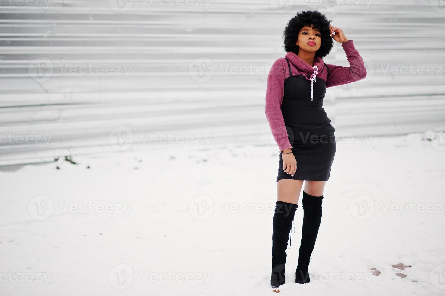 Afroamerikanerin mit lockigem Haar posierte am Wintertag. afro vorbildliches mädchen gegen schnee. foto