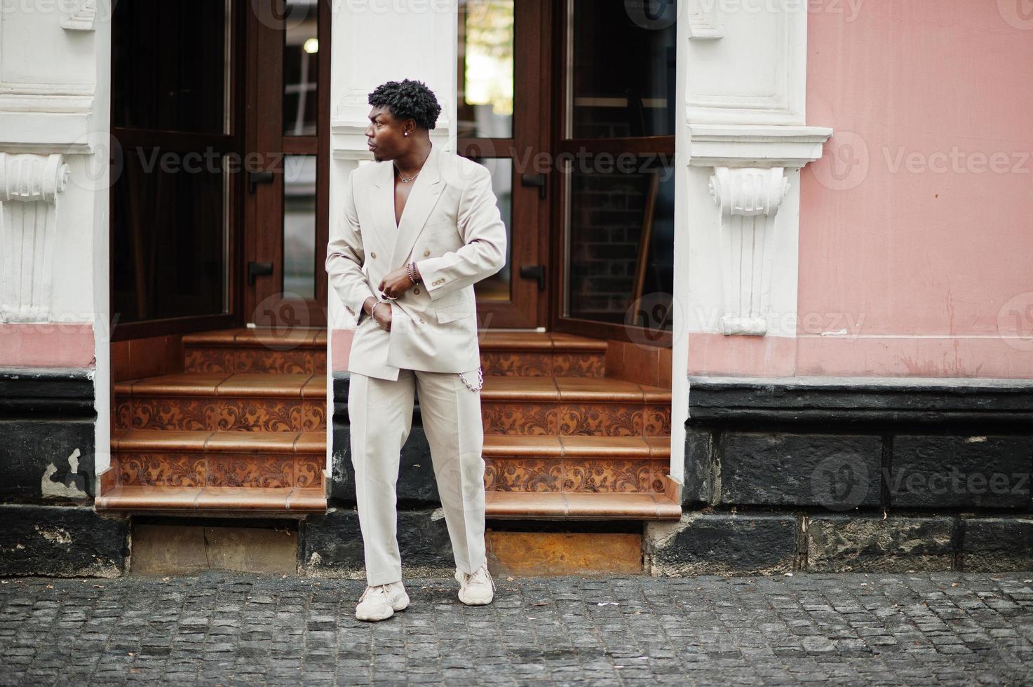 stylischer Afro-Mann im beigen Old-School-Anzug. Modischer junger afrikanischer Mann in Freizeitjacke auf nacktem Oberkörper. foto