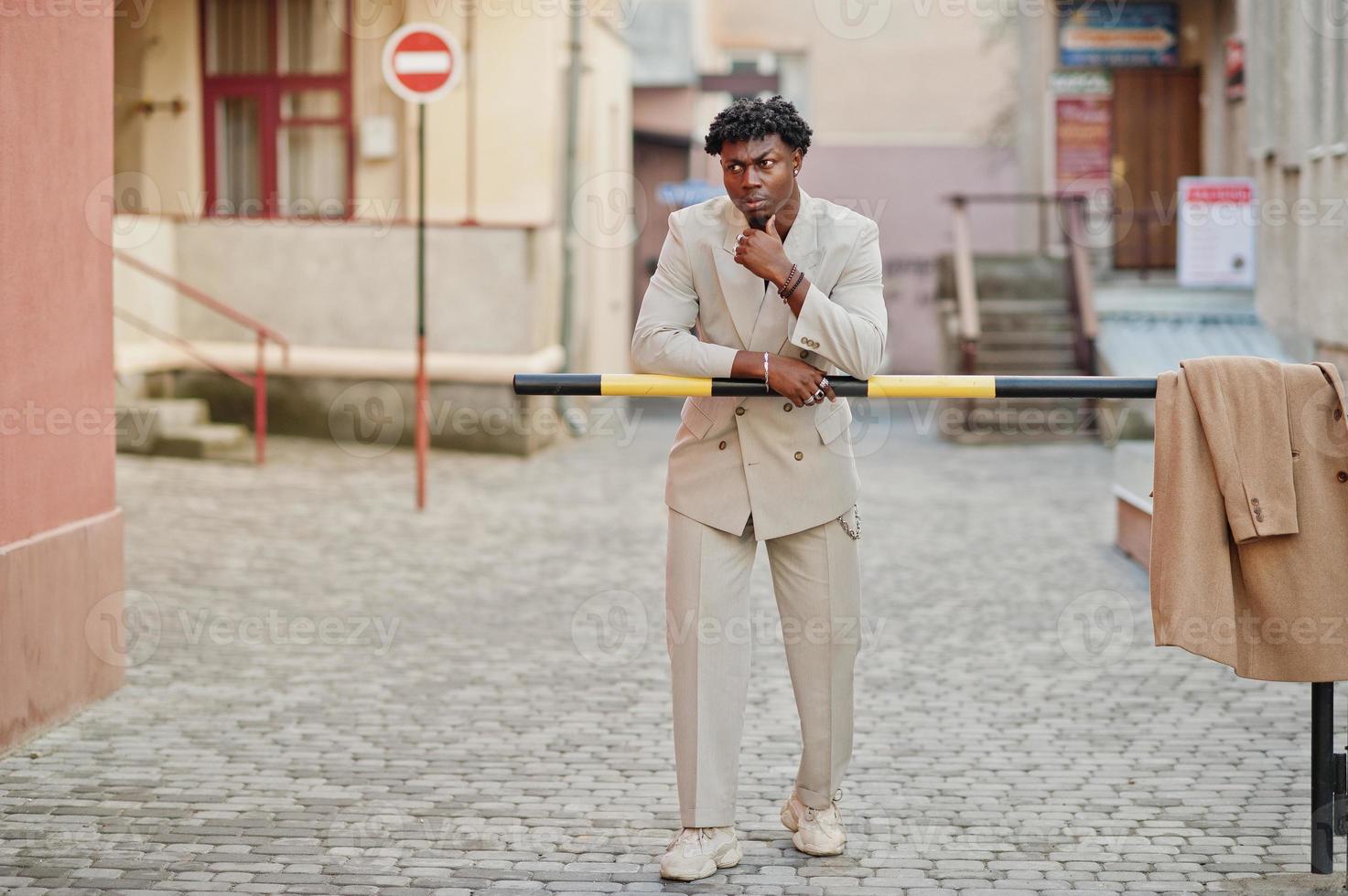 stylischer Afro-Mann im beigen Old-School-Anzug. Modischer junger afrikanischer Mann in Freizeitjacke auf nacktem Oberkörper. foto