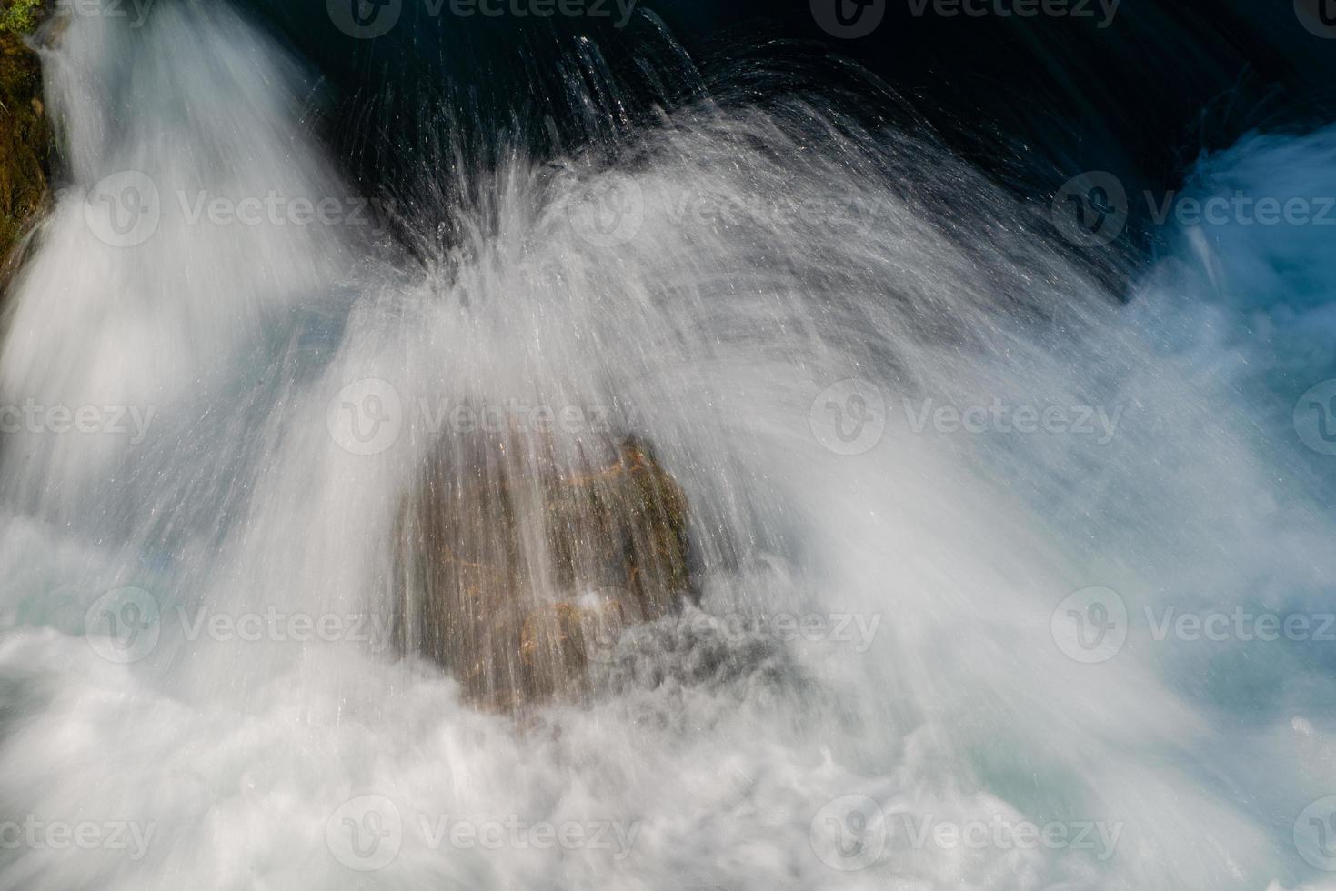 einzelner Stein im wilden Fluss foto